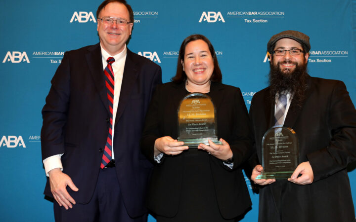 image of two men and one woman, all smiling and in business attire, with the woman and one man holding awards.